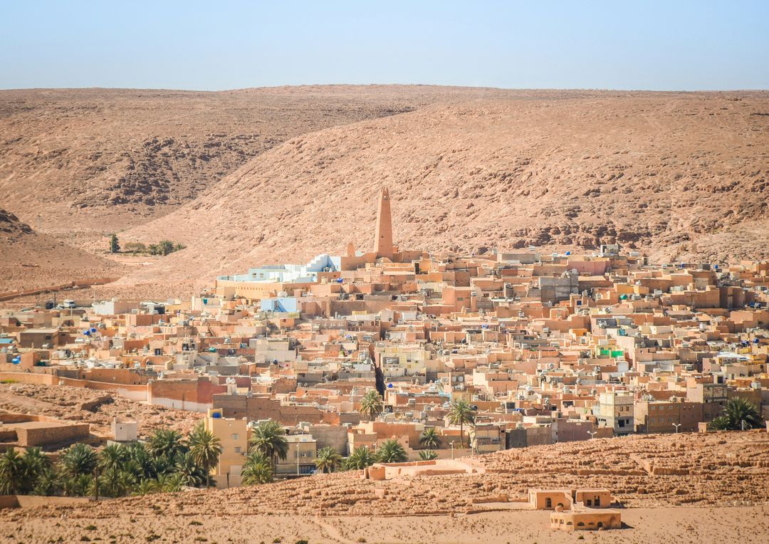 Vue de Ghardaïa dans la vallée du M’Zab : maisons ocre, palmiers et minaret au pied des collines